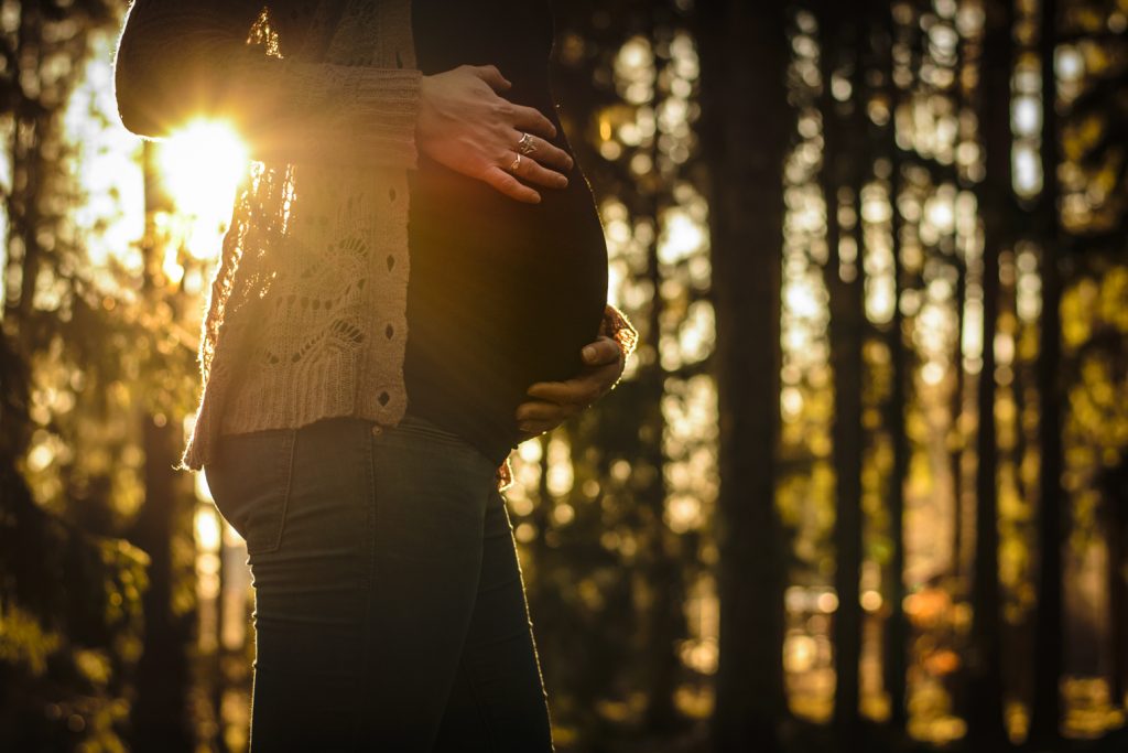 Gravid med gravidmage vanliga kläder vinter fotografering i motljus