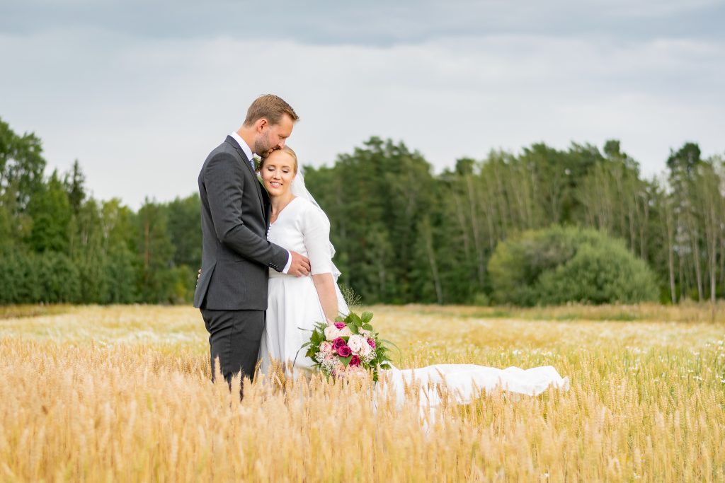 Brudpar med vintage bröllop håller om varandra på en åker i Lundby Örebro