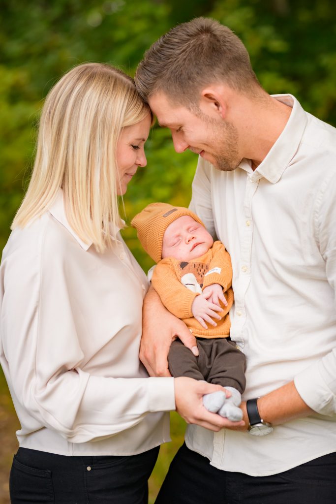 familjeporträtt med en mamma pappa och en bebis med söta kläder från Newbie. Föräldrarna har vita skjortor på sig under fotograferingen i Växjö