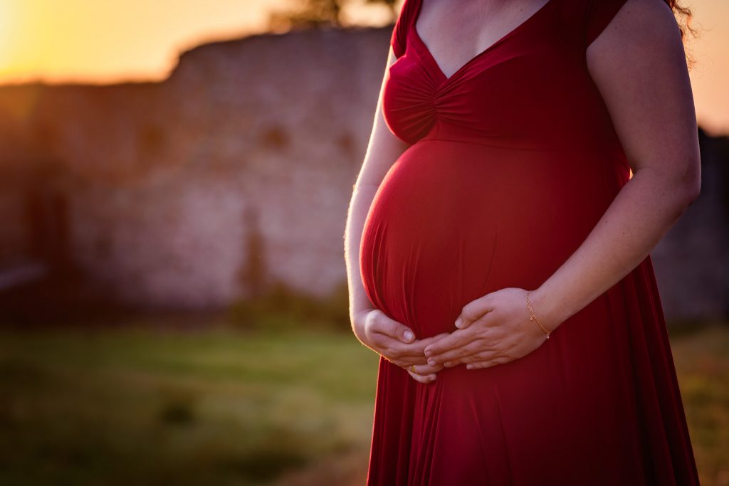 Gravidmage i röd gravidklänning från Mii Estilo Vid Kronobergs slottsruin