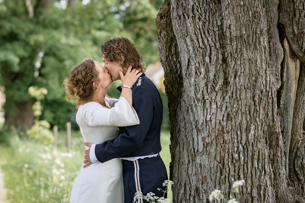 Sofia Rappe och Gustav Rappe kysser varandra vid ett träd vid Norraby Gård. Bröllop